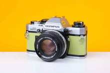 Load image into Gallery viewer, Olympus OM10 SLR vintage 35mm film camera with a Zuiko 50mm f1.8 prime lens, featuring a lime green leather skin.
