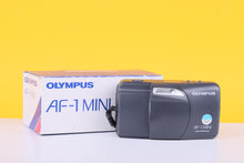 Load image into Gallery viewer, Olympus AF-1 Mini camera on a white surface with a yellow background