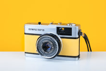 Load image into Gallery viewer, Olympus Trip 35 vintage film camera with Zuiko 40mm f2.8 lens, featuring a light yellow color, placed on a white surface against a yellow background.