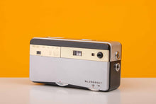 Load image into Gallery viewer, A Mamiya-16 Subminature 16mm Point and Shoot Film Camera on a white surface with an orange background.