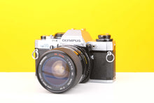 Load image into Gallery viewer, Olympus OM10 35mm SLR Film Camera with a Miranda 28-70mm lens on a yellow background.