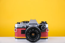 Load image into Gallery viewer, Olympus OM10 35mm SLR Film Camera with Zuiko 28mm f2.8 Prime Lens and Manual Adapter With New Leather Red and Yellow Skin