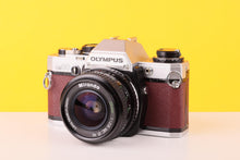 Load image into Gallery viewer, Vintage Olympus camera with leather finish on a yellow background
