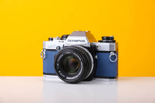 Load image into Gallery viewer, Olympus OM10 SLR Vintage 35mm Film Camera with Zuiko 50mm f/1.8 Prime Lens Reconditioned With New Blue Leather Skin

