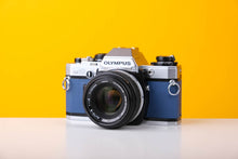 Load image into Gallery viewer, Olympus OM10 Slr Vintage 35mm Film Camera with Zuiko 50mm f/1.8 Prime Lens Reconditioned With New Blue Leather Skin
