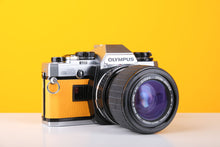 Load image into Gallery viewer, Olympus OM10 35mm SLR Film Camera in Yellow with Sigma 35-70mm f/2.8 Zoom Lens
