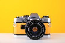 Load image into Gallery viewer, Olympus OM10 35mm SLR Film Camera in Yellow with Sigma 35-70mm f/2.8 Zoom Lens

