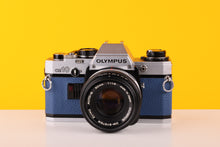 Load image into Gallery viewer, Olympus OM10 SLR Vintage 35mm Film Camera with Zuiko 50mm f/1.8 Prime Lens Reconditioned With New Blue Leather 

