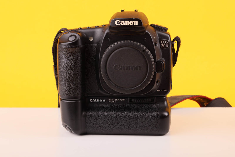 Canon camera body with battery grip on a yellow and white background