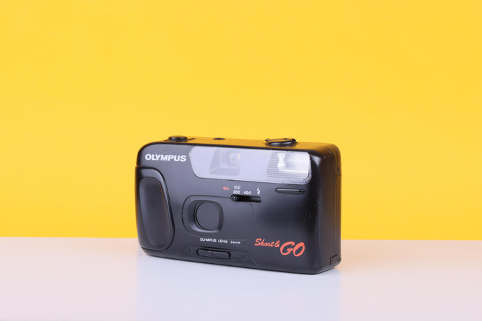 Black Olympus camera with 'Shot & Go' text on a yellow background