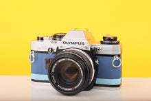 Load image into Gallery viewer, Olympus OM10 SLR Vintage 35mm Film Camera with Zuiko 50mm f/1.8 Prime Lens Reconditioned With New Blue Leather Skin
