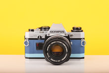 Load image into Gallery viewer, Olympus OM10 SLR Vintage 35mm Film Camera with Zuiko 50mm f/1.8 Prime Lens Reconditioned With New Blue Leather Skin

