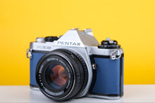 Load image into Gallery viewer, A Pentax ME Super 35mm SLR film camera with a blue leather skin and SMC Pentax-M 50mm f1.7 lens, displayed against a yellow background.
